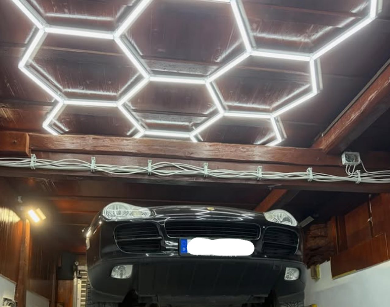 Fahrzeug auf der Hebebühne in der modernen Werkstatt mit Hexagon-Beleuchtung